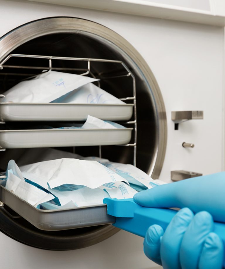 Young male dentist places medical autoclave for sterilising surgical and other instruments